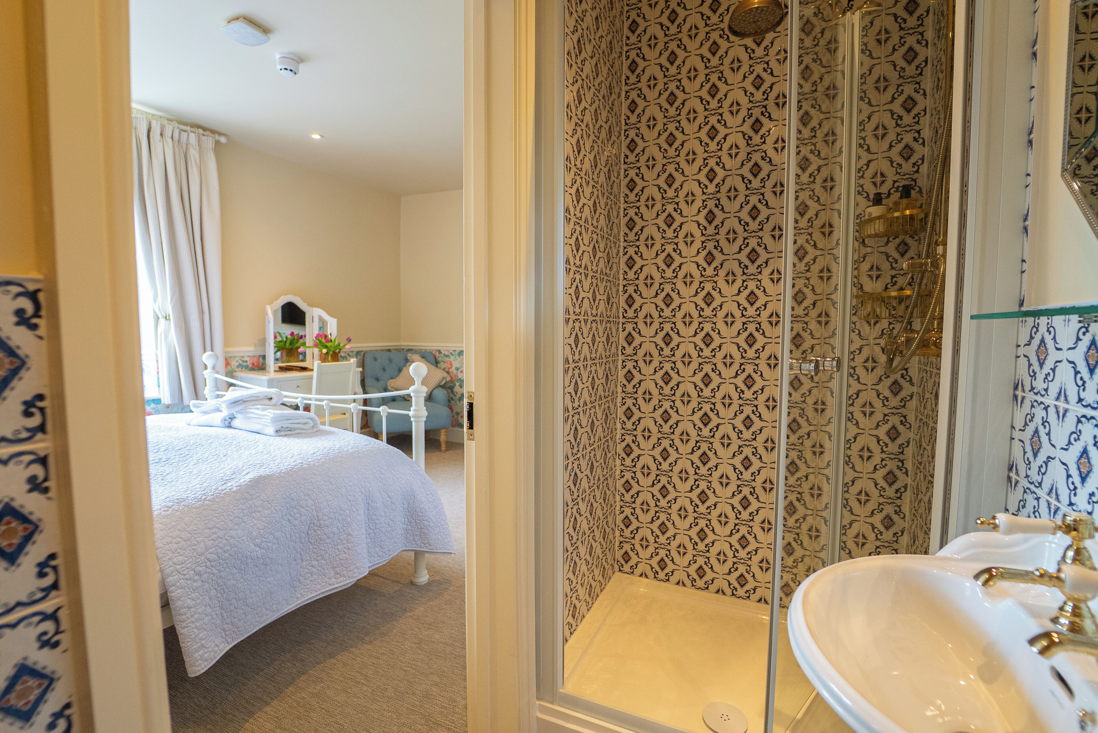A hotel room with a bed, a bathroom with a patterned shower wall, and a sink.