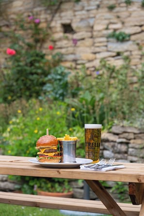 A picnic table with a burger, fries, and a beer glass. - The Market Tavern (Bampton)