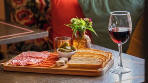 A dining table with a tray of food, a glass of red wine, and a small vase with flowers. - The Market Tavern (Bampton)