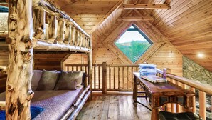 A cozy cabin with a loft bedroom, a dining area, and a large window offering a view of the outdoors. - Resort Pool Fitness Room Hot Tub Jacuzzi (Gatlinburg)
