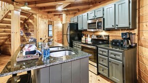 A wooden cabin kitchen with granite countertops, stainless steel appliances, and a built-in island with a sink. - Resort Pool Fitness Room Hot Tub Jacuzzi (Gatlinburg)