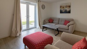 Una sala de estar con sofá, reposapiés y mesa de centro.