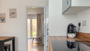 Una cocina moderna con encimera de madera, una tetera y un comedor con mesa y bancos.