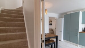 Una escalera que lleva a una habitación con una mesa de madera y un refrigerador.