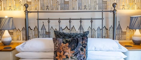 Classic design with a bed, bedside tables, and a mural of houses adorns the wall.