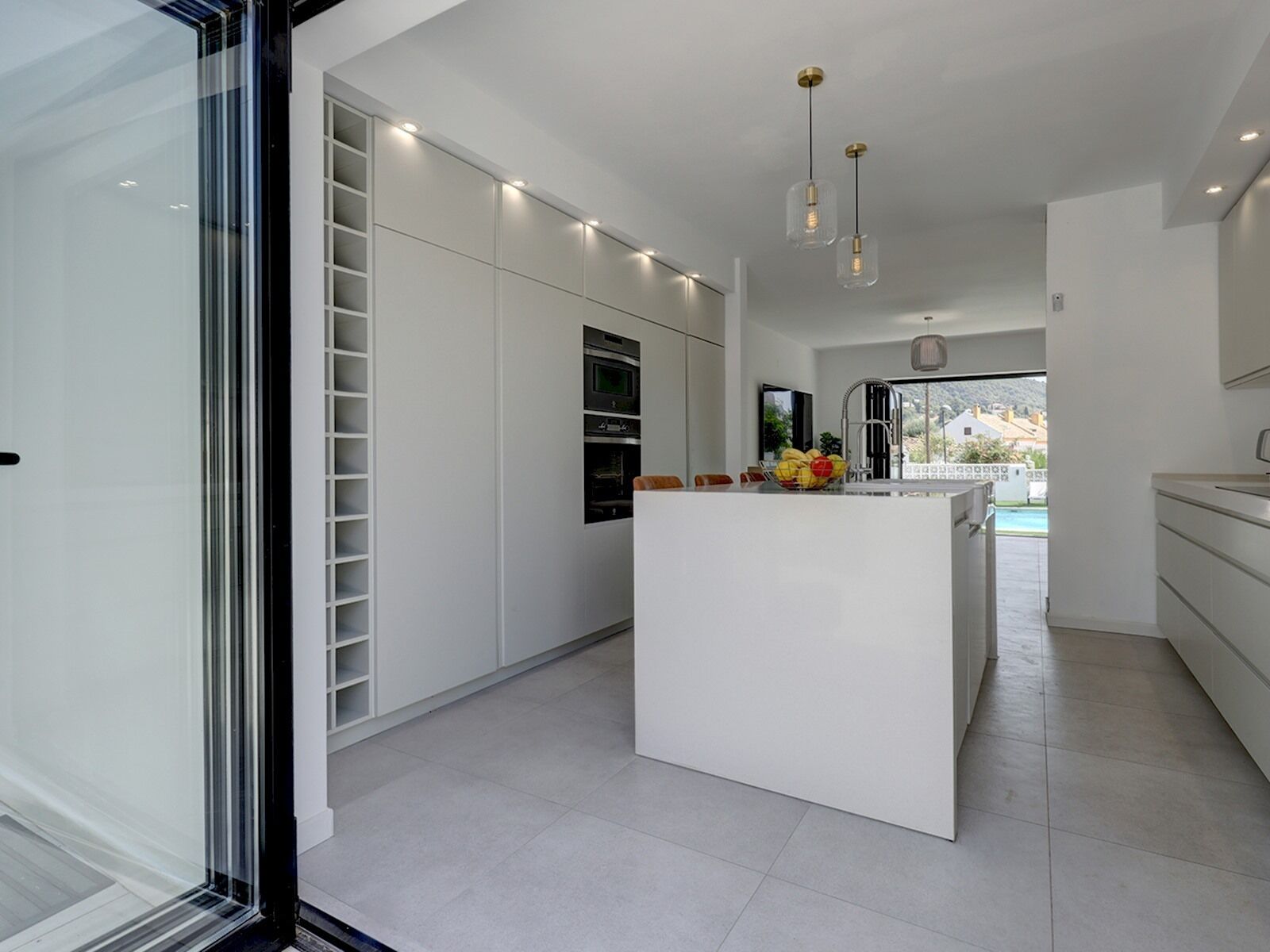 A modern kitchen with white cabinetry, a central island, and a built-in oven.