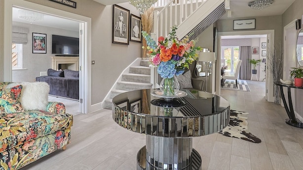 Un salon avec un canapé, un téléviseur et un escalier surmonté d’un lustre.