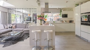Une cuisine moderne dotée d’un îlot central, de tabourets de bar et d’un coin repas comprenant un canapé et une table basse.