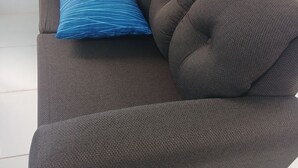 A dark brown sofa with a tufted backrest and a single blue patterned pillow. - Blue Song Villa (Rio Bueno)