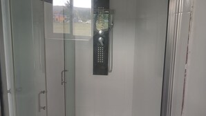 A glass-enclosed shower stall with a control panel and a view of the outside. - Blue Song Villa (Rio Bueno)
