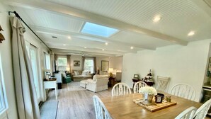 Un amplio espacio de sala con una mesa de comedor de madera, sillas blancas y un sofá.