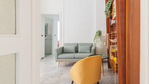 A living room with a sofa, a yellow chair, and a bookshelf. - JOIVY Charming 2BR flat near the Duomo (Milan)