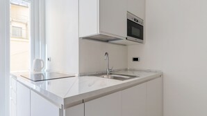 A modern kitchen with white cabinetry, a stainless steel sink, and a built-in oven. - JOIVY Charming 2BR flat near the Duomo (Milan)