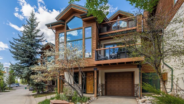 A two-story house with a large garage, a balcony on the second floor, and a driveway leading to the entrance. - 4bd Townhome, Mtn Views, Pool & Hot Tub 1079 (Steamboat Springs)