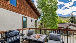 A patio with a grill, a table with a fire pit, and two chairs. - 4bd Townhome, Mtn Views, Pool & Hot Tub 1079 (Steamboat Springs)