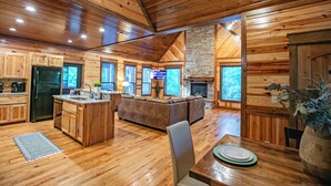 A spacious log cabin interior with a kitchen, dining area, and living room. - River Song- 1BR-Timber Creek Trails-Creekside (broken bow)