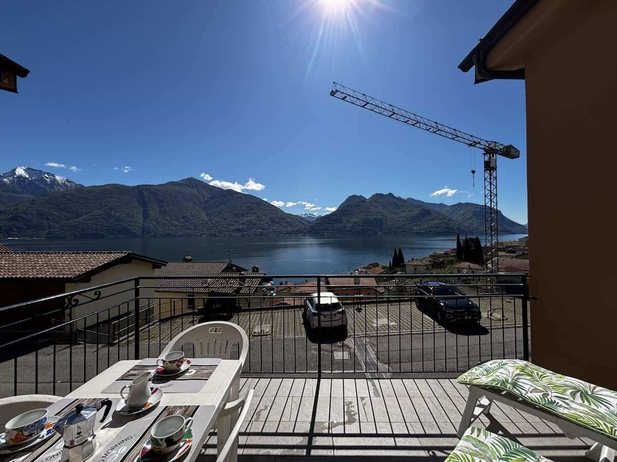 A balcony with a view of a lake, mountains, and a parked car.