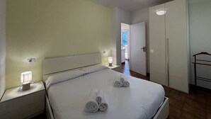 Ein Hotelzimmer mit Bett, Nachttischen, einem Schrank und Blick nach draußen.
