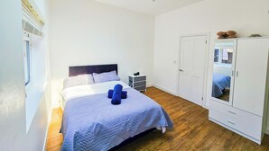A bedroom with a bed, a wardrobe, a small bedside table, and a skylight.