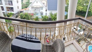 A balcony with a wrought iron railing, a round table, and a small seating area.