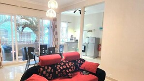 A modern living room with a red sofa, a dining area with a table and chairs, and a kitchen in the background.