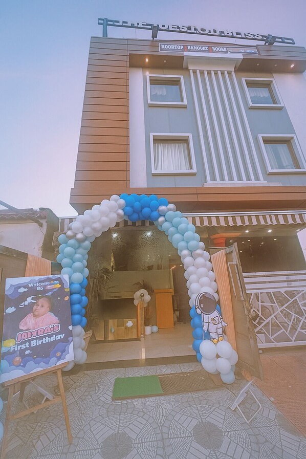 L’entrée d’un hôtel, agrémentée d’une arche de ballons bleus et blancs, d’une pancarte de bienvenue et de décorations d’anniversaire pour Jattra.