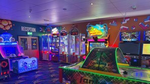 Un salón de juegos recreativos con diversas máquinas, una zona de recepción y un juego con temática de motocicletas.