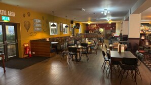 Interior de restaurante con cabinas y mesas, una zona de bar, y un cartel que dice 'Good Food' en la pared.
