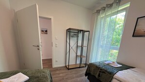Une chambre avec deux lits, une armoire et une fenêtre avec des rideaux.