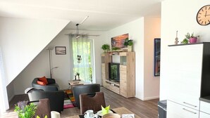 Un salon moderne comprenant un canapé, une table à manger et des chaises, un téléviseur et une cheminée.
