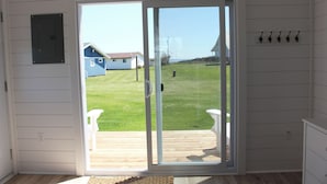 Una habitación con puerta corrediza de vidrio que da a una terraza de madera.