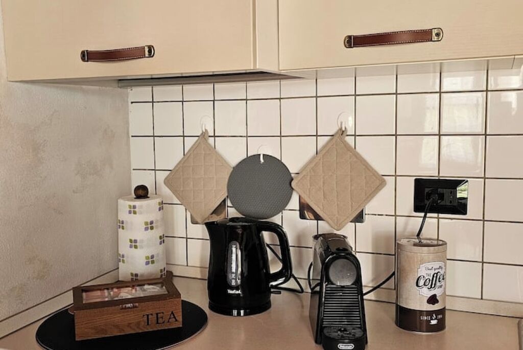 A kitchen counter with a coffee maker, a kettle, a box labeled "TEA", and a canister of coffee.