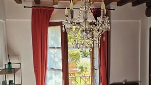 A room with a chandelier, red curtains, a view to the outside, and a radiator.