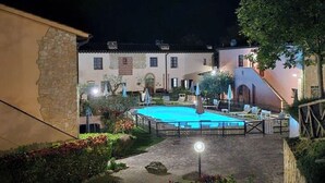 A courtyard with a swimming pool, lounge chairs, and umbrellas.