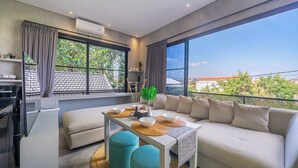 Ein modernes Wohnzimmer mit einer Couch, einem Couchtisch und Blick ins Freie.