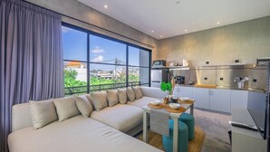 Ein modernes Wohnzimmer mit einer Couch, einem Esstisch mit Schüsseln und einer Küchenzeile mit Edelstahlgeräten.