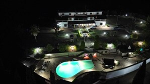 A hotel with a swimming pool, outdoor seating, and a well-lit parking area at night. - Villa Maria Pia - Roman Elegance Immersed in the Green (Aranova)
