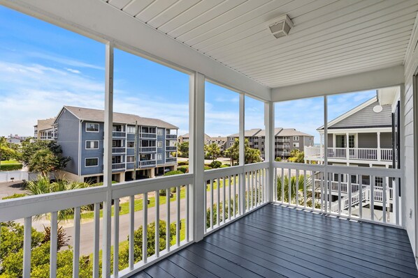 A covered outdoor balcony with a view of residential buildings.