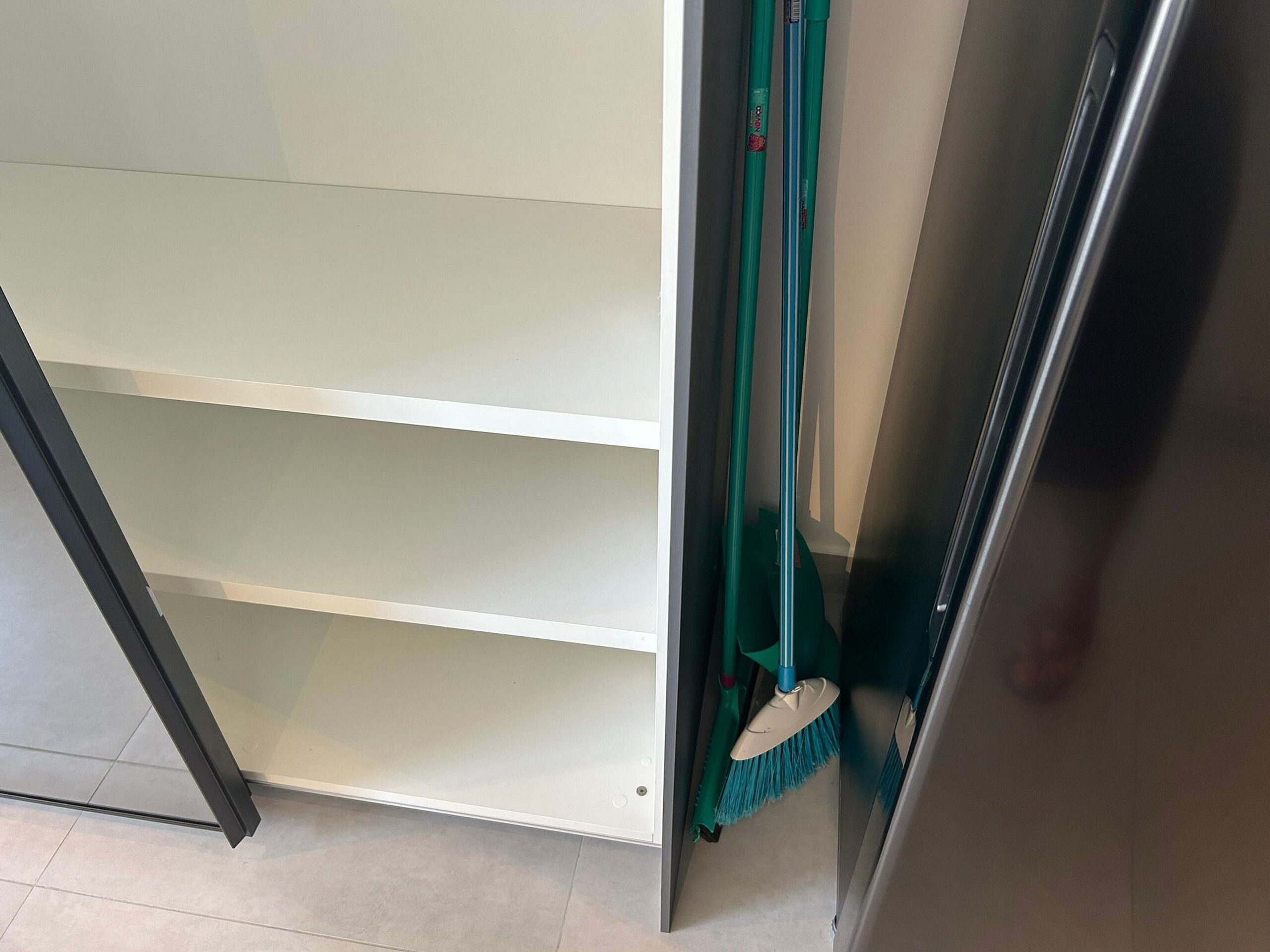 A partially open door with a broom leaning against it.