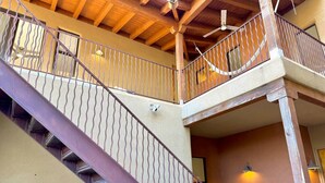 A multi-level wooden staircase with metal railings, a ceiling fan, and wall-mounted lights.