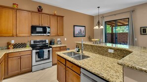 A kitchen with wooden cabinets, stainless steel appliances, granite countertops, and a large window with a view.