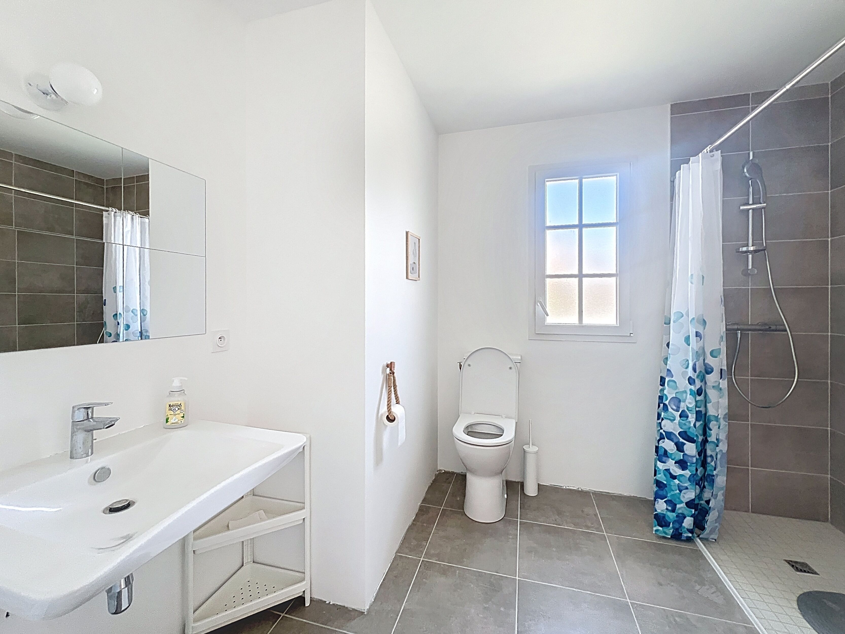 A bathroom with a white sink, toilet, and shower area.