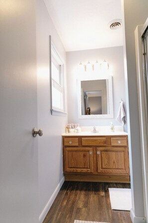A bathroom with a wooden vanity, a large mirror, and a white sink.