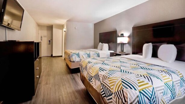 A hotel room with two beds, a TV, a desk, and a lamp. - Home Place Suites (Bartlesville)