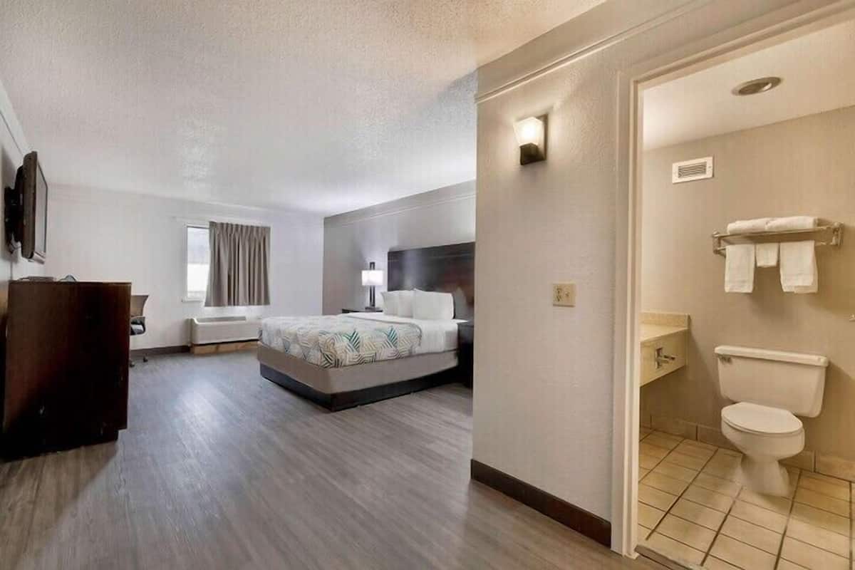 A hotel room with a bed, bedside table, and a bathroom with a toilet and sink.
