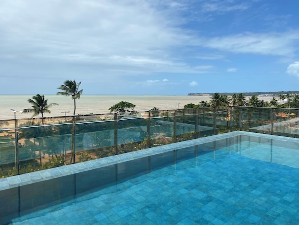 Una piscina al aire libre, sombrillas, sillones reclinables de piscina