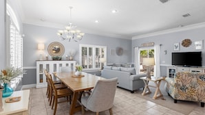 A spacious living room with a dining area, a sofa, and a TV. - Hot Tub, Sleeps 10, 1 block to beach access, Pets (Panama City Beach)
