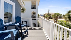 A balcony with Adirondack chairs, a white railing, and a view of the beach and other buildings. - Hot Tub, Sleeps 10, 1 block to beach access, Pets (Panama City Beach)