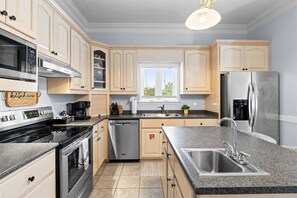 Una cocina moderna con gabinetes de madera clara, electrodomésticos de acero inoxidable y encimera de granito.