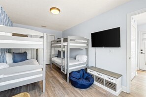 A room with bunk beds, a flat-screen TV, and a bean bag chair. - Hot Tub, Sleeps 10, 1 block to beach access, Pets (Panama City Beach)